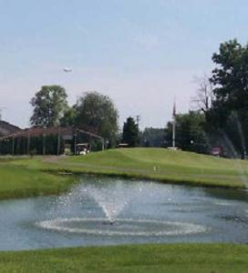 two fountains spraying up in the pond on the golf course, club house is situated up the hill behind the pond