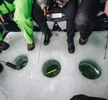 A group of people in a circle ice fishing