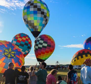 field of flight air show - hot air balloons starting to rise on a sunny day