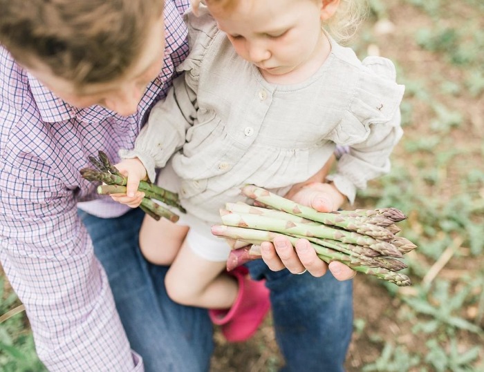 Child and parent holding asparagus