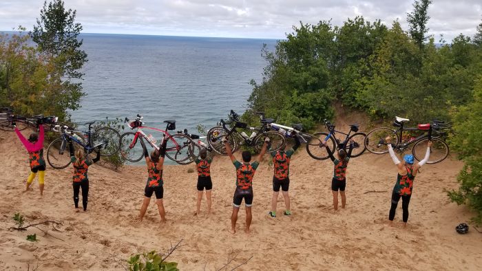 Bikers hold up bikes in celebration and overlook Lake Superior