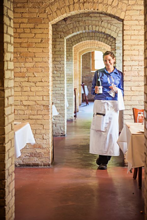 Waitress with wine bottle and glasses in restaurant