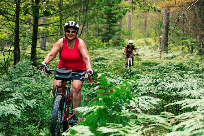Woman and man mountain biking in forest.