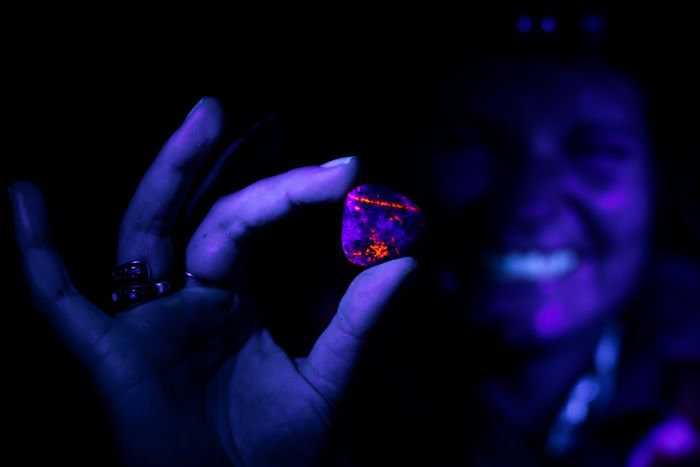 Woman holding Yooperlite rock under UV light